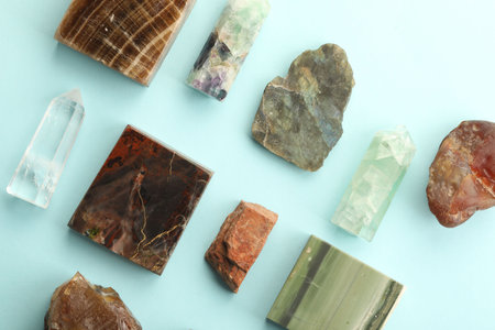 Beautiful natural gemstones on light blue background, flat lay