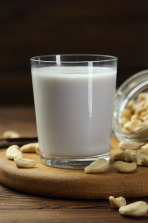 Fresh cashew milk in glass and nuts on wooden table, closeupの写真素材