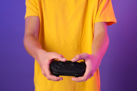 Teenage boy playing video game with controller on purple background, closeupの写真素材