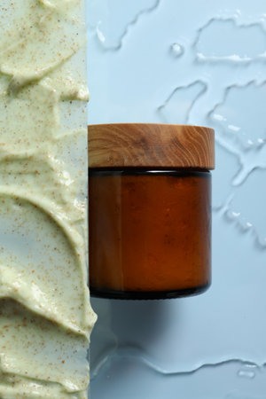 Cosmetic jar and sample of body scrub on light background, top view
