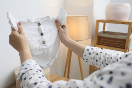 Woman with baby clothes at home, closeupの写真素材