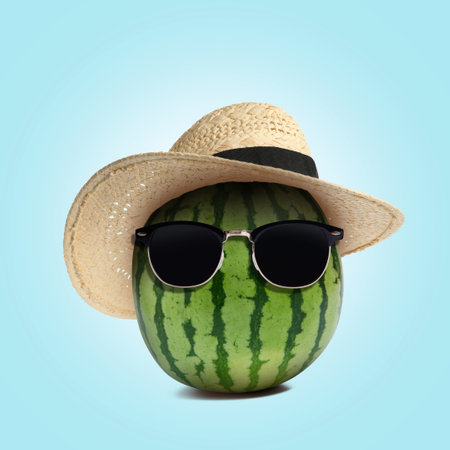 Watermelon with straw hat and sunglasses on light blue backgroundの写真素材