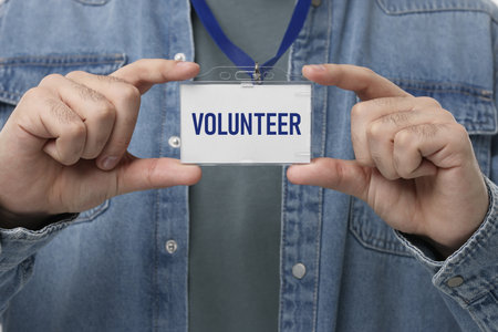 Man holding badge with word Volunteer, closeup