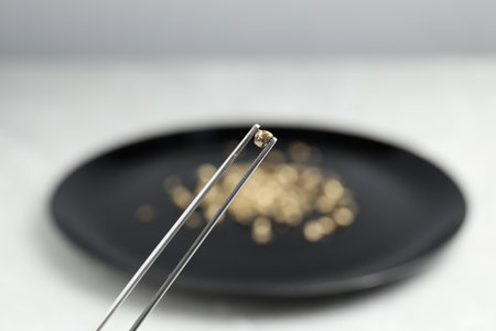 Tweezers with gold nugget against blurred background, closeupの写真素材