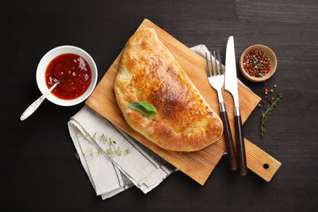 Delicious fresh calzone pizza served on wooden table, flat layの写真素材