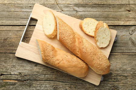Cut fresh baguette with sesame on wooden board, top viewの写真素材
