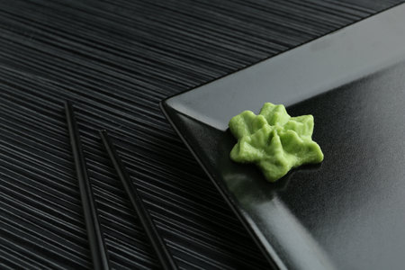 Plate with hot wasabi paste and chopsticks on black textured table, closeupの写真素材