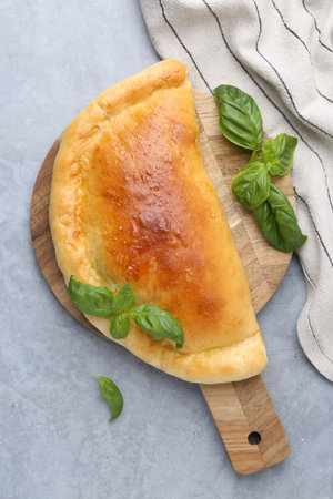 Tasty vegetarian calzone with basil on gray table, top viewの写真素材