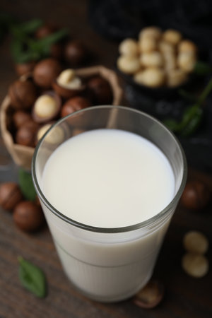 Glass of macadamia milk and nuts on wooden table, closeupの写真素材