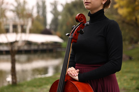 Young woman with cello in park, closeup. Space for text