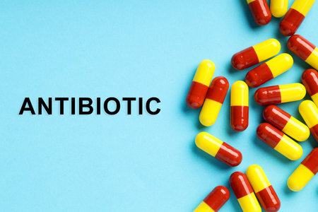 Word Antibiotic and pills on light blue background, top viewの写真素材