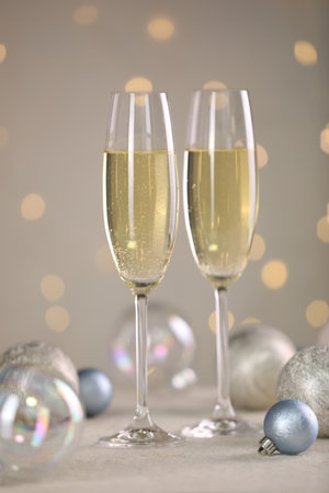 Delicious champagne in glasses and Christmas decor on white table against blurred lightsの写真素材