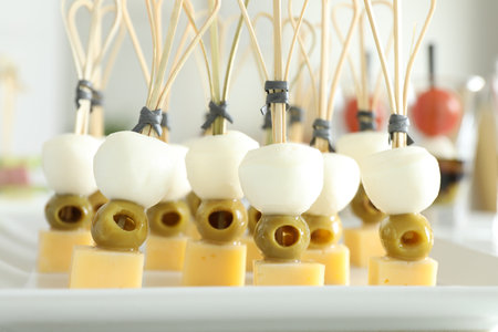 Tasty canapes with different types of cheese and green olives on white table, closeupの写真素材