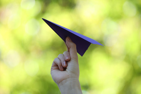 Woman with handmade paper plane on blurred green background, closeupの写真素材
