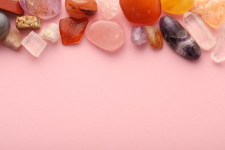 Beautiful natural gemstones on light pink background, flat lay. Space for textの写真素材