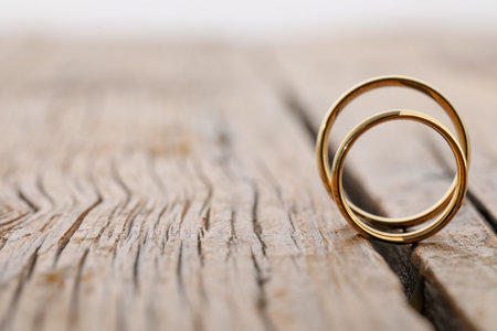 Beautiful golden wedding rings on wooden background, space for textの写真素材