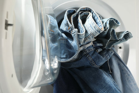 Washing machine with dirty jeans and other denim clothes indoors, closeupの写真素材
