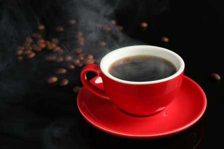 Red cup with coffee and roasted beans on black background, closeupの写真素材