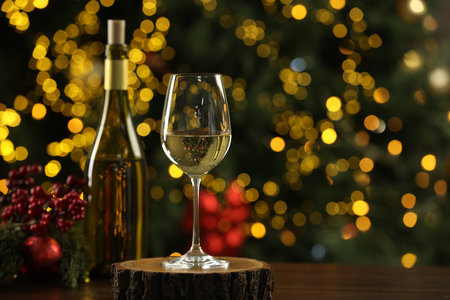 Glass and bottle of white wine with Christmas decor on wooden table against blurred lights, space for text. Bokeh effectの写真素材