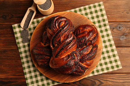 Tasty buns with poppy seeds on wooden table, flat lay