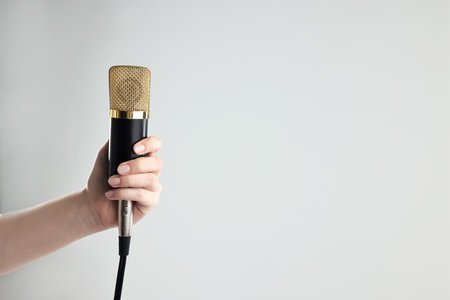 Woman with microphone on gray background, closeup. Space for textの写真素材