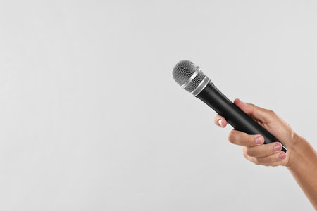 Man with microphone on light gray background, closeup. Space for textの写真素材