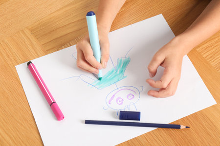 Boy drawing picture at wooden table, above view