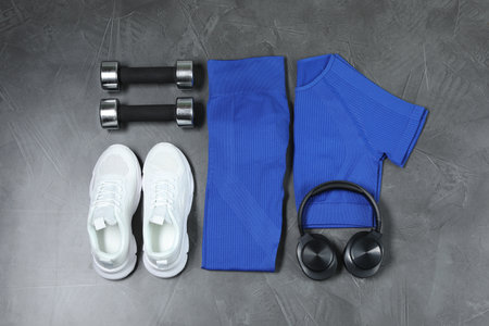 Stylish sportswear, white sneakers, dumbbells and headphones on gray background, flat layの写真素材