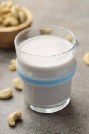 Fresh cashew milk in glass and nuts on gray textured table, closeupの写真素材