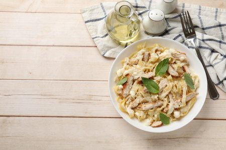 Tasty Alfredo pasta with chicken served on light wooden table, flat lay. Space for textの写真素材