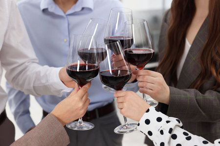 Happy coworkers clinking glasses of wine during office Christmas party, closeupの写真素材