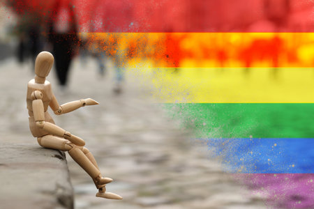 Wooden human figure sitting on curb outdoors and LGBT flag, double exposure.の写真素材
