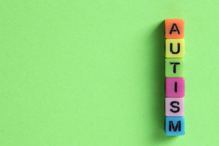 Word Autism made with colorful cubes on green background, flat lay. Space for textの写真素材