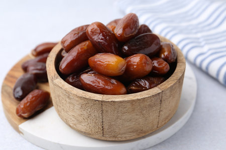 Tasty dried dates in wooden bowl on white table, closeupの写真素材
