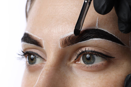 Young woman undergoing henna eyebrows dyeing on light background, closeupの写真素材