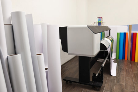 Wide-format printer and paper rolls indoors. Printing house