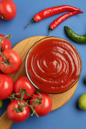 Tasty ketchup and vegetables on blue background, flat layの写真素材