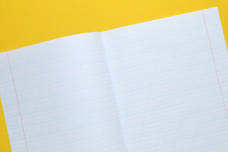 Open copybook on yellow background, top viewの写真素材