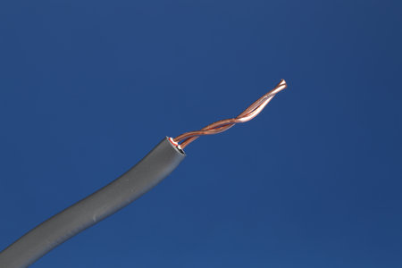 Grey stripped electrical wire on blue background, closeup
