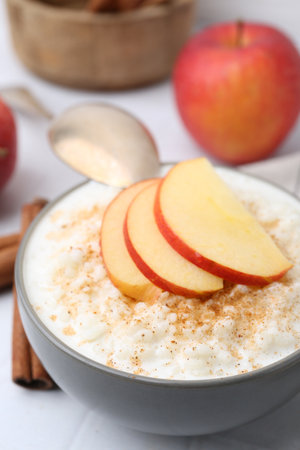 Delicious rice pudding with apples and cinnamon on white table, closeupの写真素材