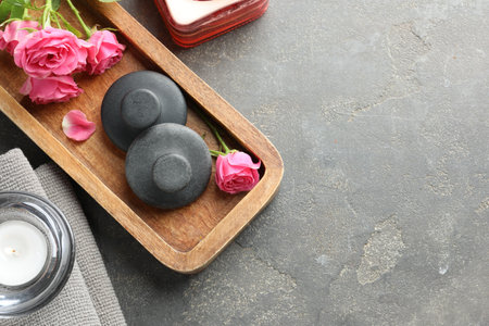 Spa stones, rose flowers and candles on grey table, flat lay. Space for textの写真素材