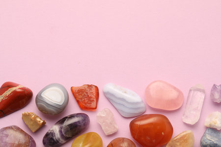Beautiful natural gemstones on light pink background, flat lay. Space for textの写真素材