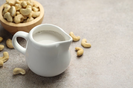 Fresh cashew milk and nuts on grey textured table, closeup. Space for textの写真素材