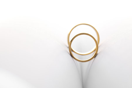 Beautiful golden wedding rings on light background, space for textの写真素材