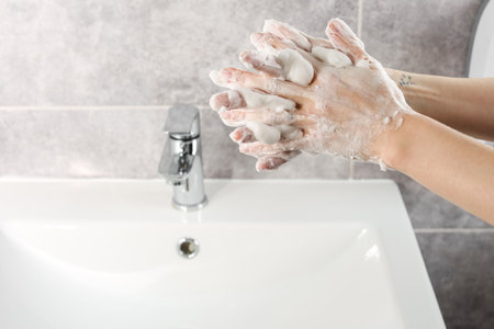 Woman washing hands with cleansing foam near sink in bathroom, closeup. Space for textの写真素材