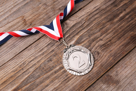 Silver medal with striped ribbon on wooden background, above viewの写真素材