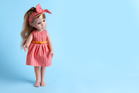 Beautiful doll in dress and headband on light blue background. Space for textの写真素材