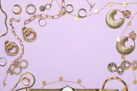 Frame made of golden jewelry on violet background, flat lay. Space for textの写真素材