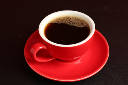 Red cup with coffee on black table, closeupの写真素材