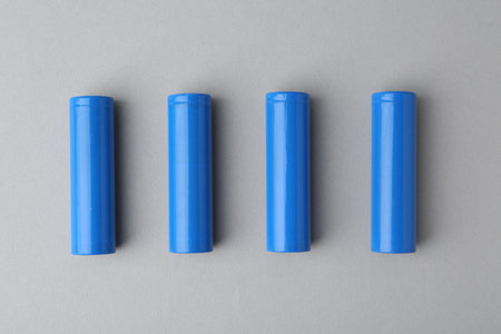 Four blue cylindrical batteries on light grey background, top viewの写真素材